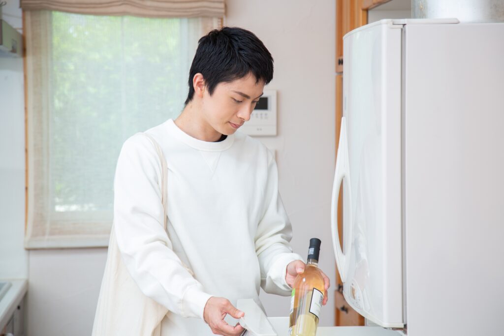 ワインを冷蔵庫に入れる男性